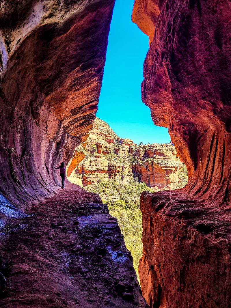 A woman standing on the ledge of "The Subway" cave in Sedona