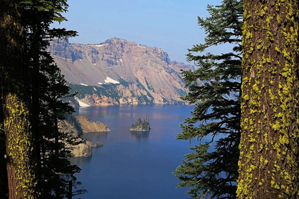A view of Crater Lake between two trees at Crater Lake National Park, one of the most underrated national parks in the US