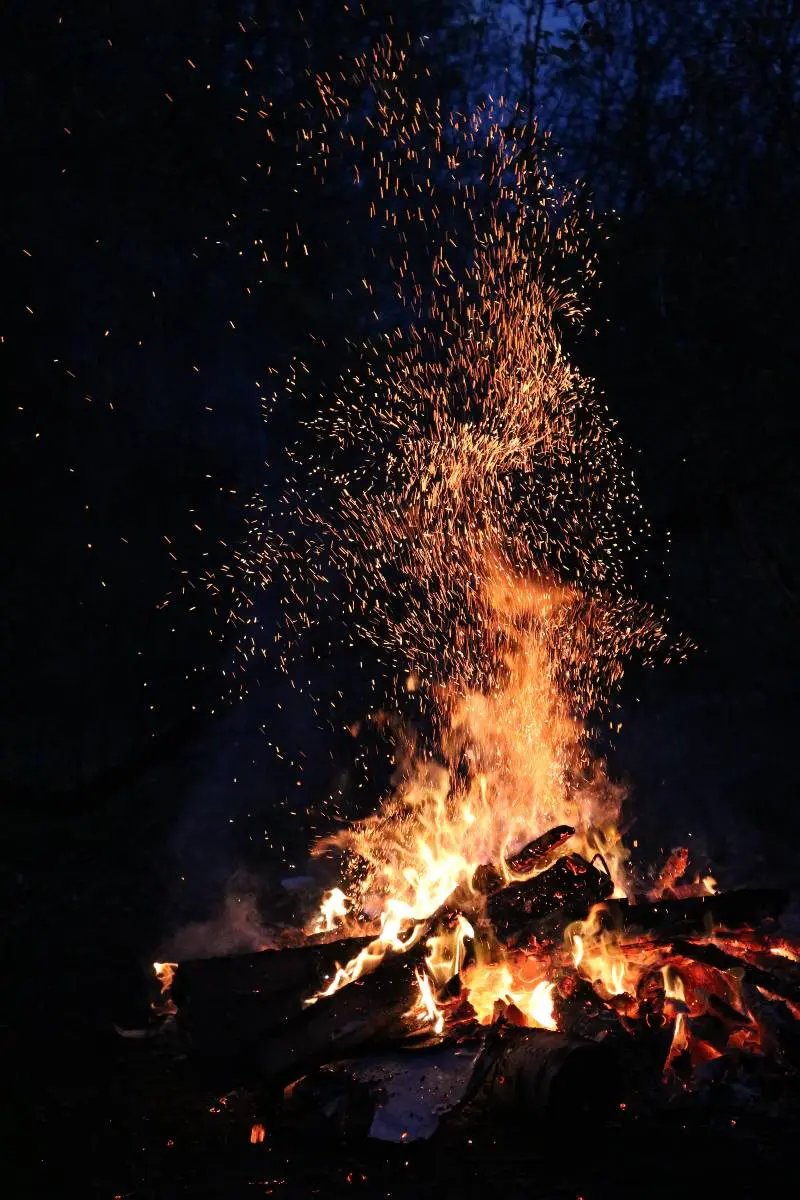 A campfire with embers sparking off at night
