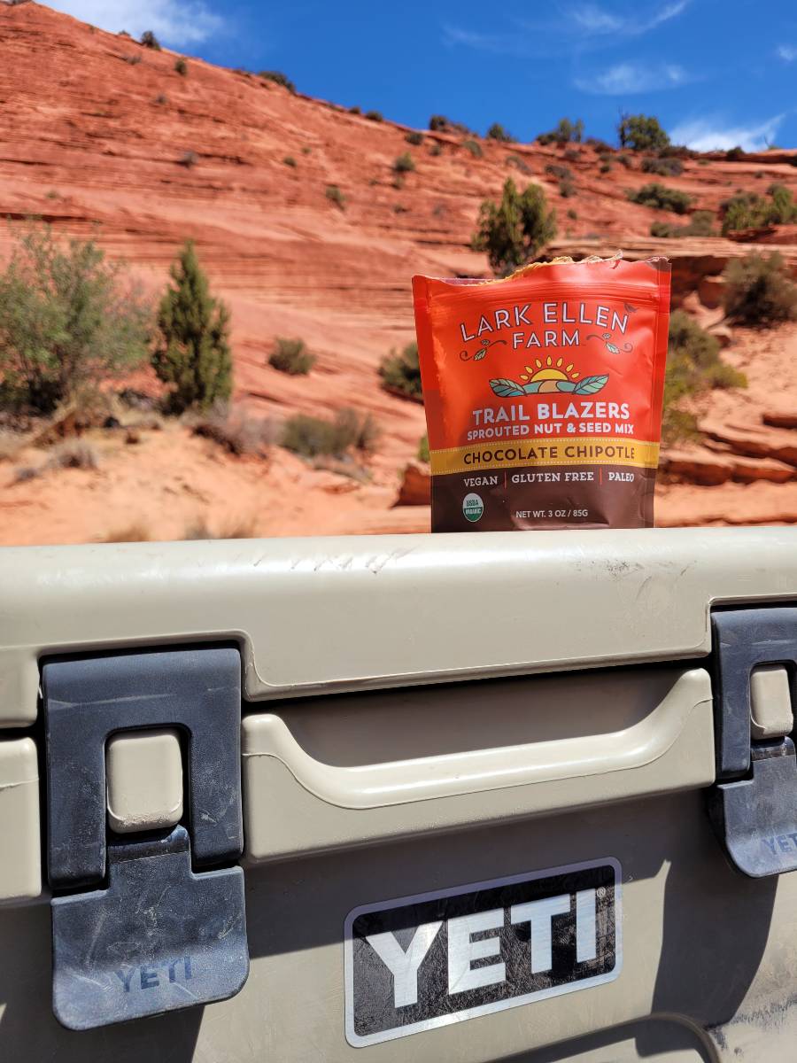A bag of granola sitting on top of a YETI cooler, one of the most important camping must haves, in front of red rocks in Utah