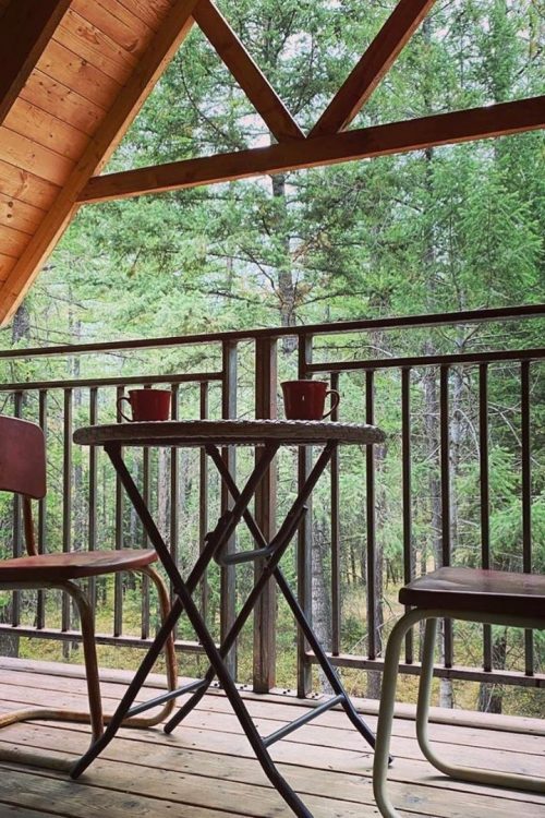 Two chairs and a table on the deck at Montana Treehouse Resort, a perfect option for Montana glamping