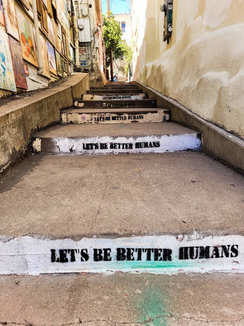 A concrete staircase in Bisbee, Arizona, with the words "Let's be better humans" painted on them