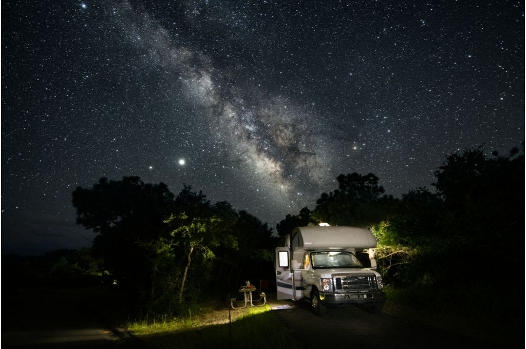 An RV parked in a Harvest Hosts location under the milky way at night