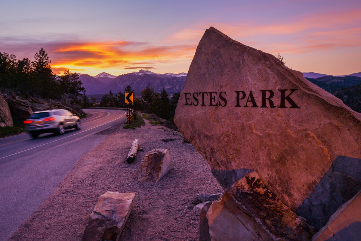 The iconic Estes Park rock welcome sign next to the road during sunset in Estes Park, one of the best Colorado mountain towns