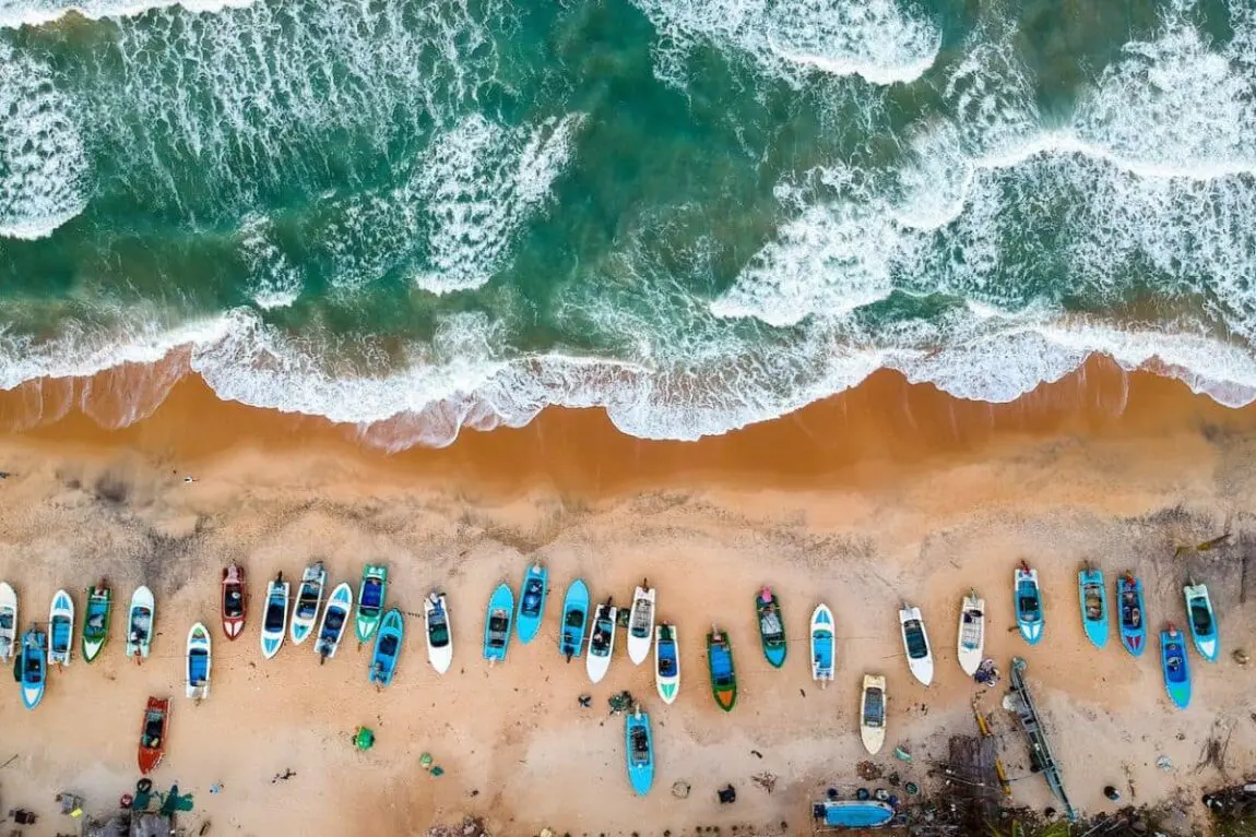 Dozens of boats on shore with waves crashing in Sri Lanka, one of the best places to visit with friends