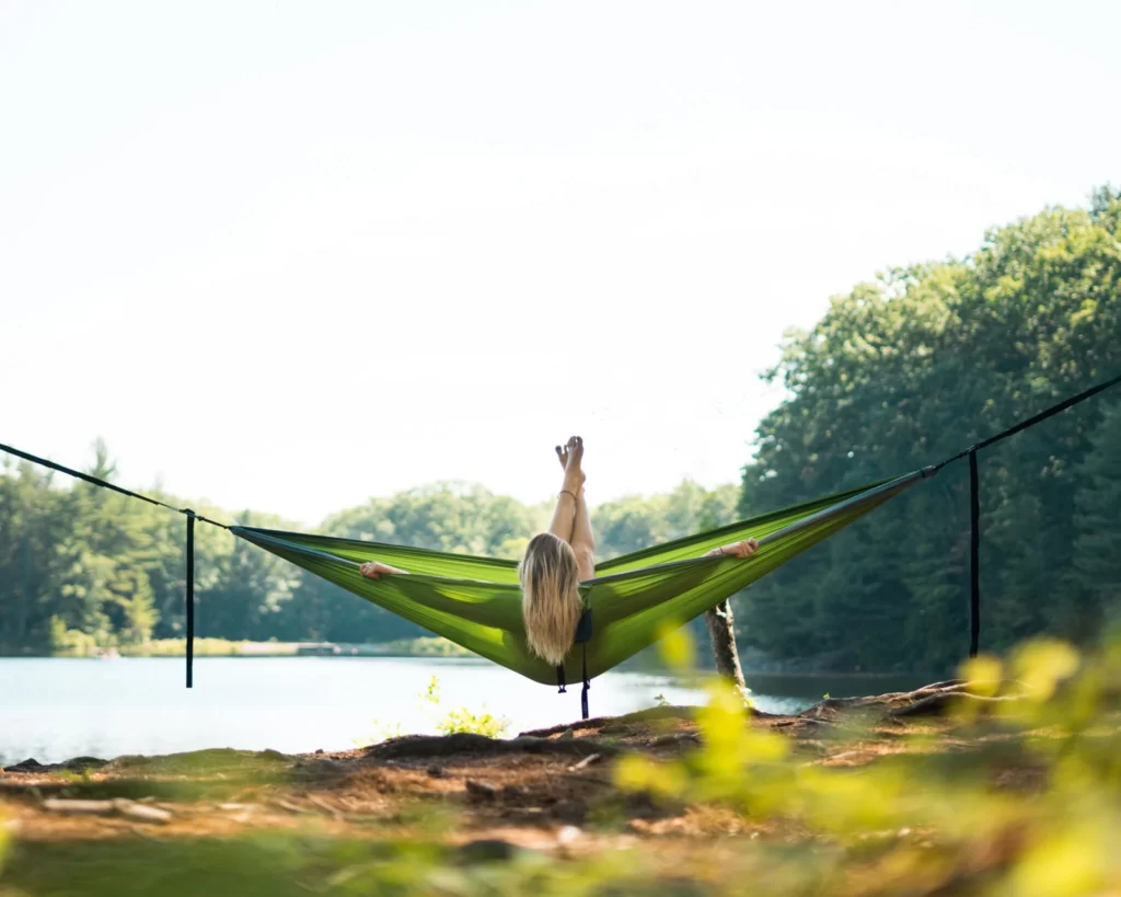 A woman relaxing with her feet up in a green ENO hammock, one of the best outdoorsy gifts for her