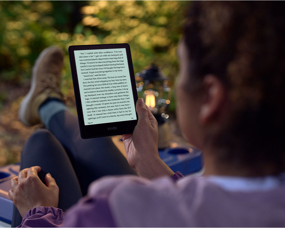 A woman reading on a Kindle Oasis, one of the best gifts for outdoorsy women