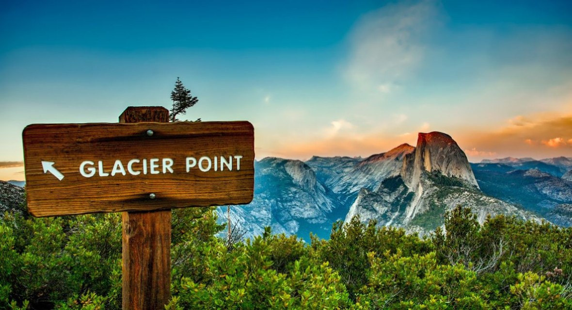 A sign for Glacier Point sign with a view of Half Dome in the background