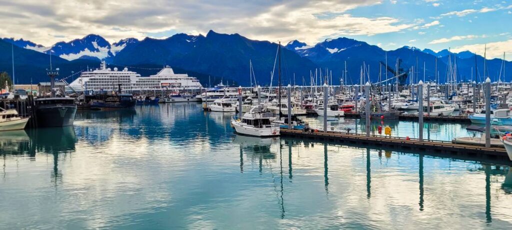 A cruise ship and numerous other boats in front of the mountains in the Seward boat harbor