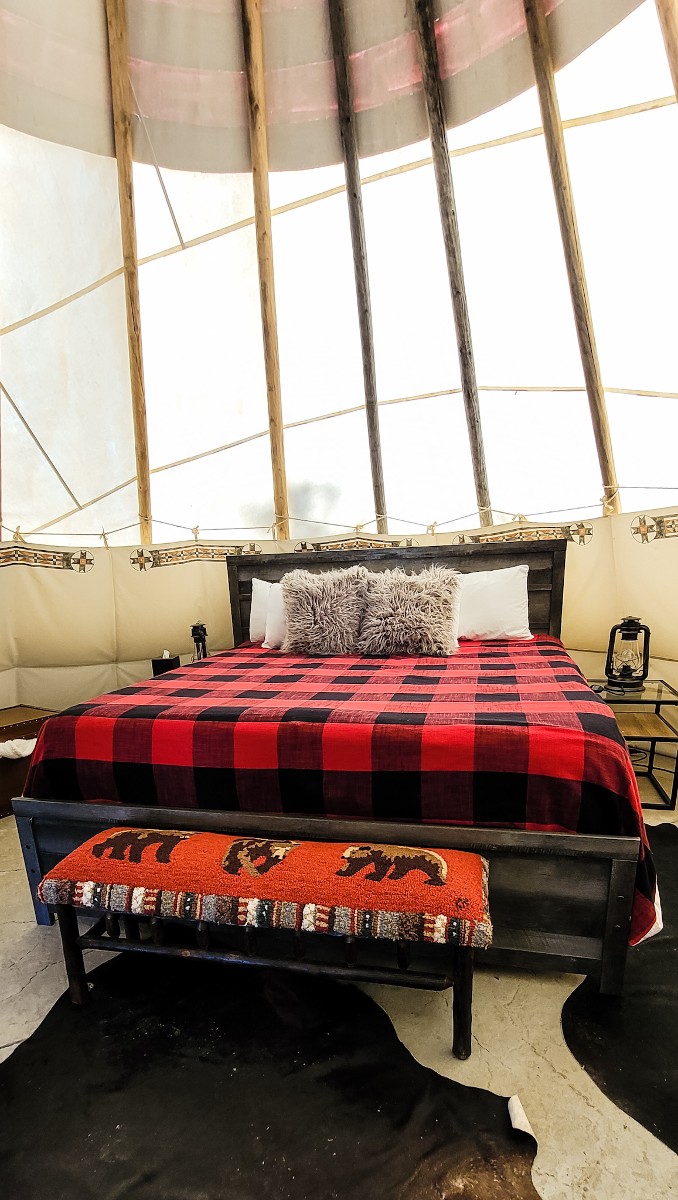 view of the bed and interior of tipi at yellowstone glamping property