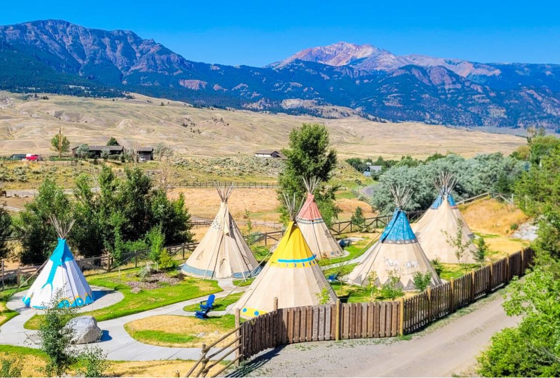 An aerial view of the colorful tipis and the surrounding valley and mountains at a Yellowstone glamping resort