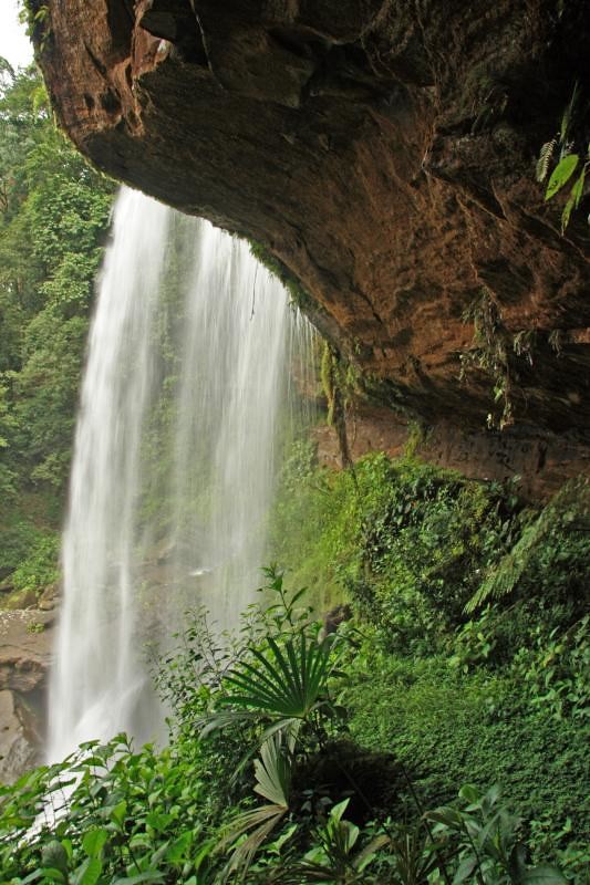 back view of water flowing from a Costa Rica waterfall, from the perspective of a cave behind it