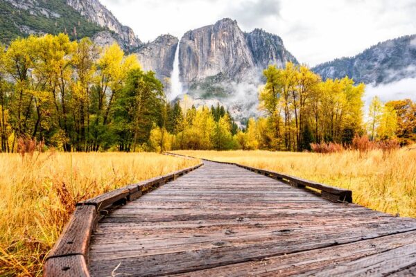 A boardwalk trail section of one of the easy hikes in Yosemite Valley, surrounded by fall foliage and waterfalls