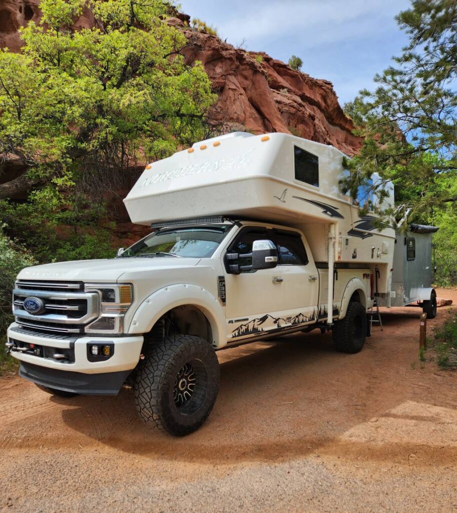 A truck with a camper shell attached parked in a campsite at Calf Creek Campground