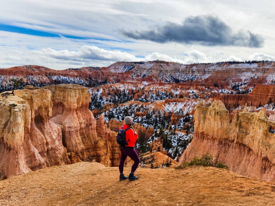 A woman wearing a purple pair of outdoor leggings and a bright red jacket in Bryce Canyon National Park