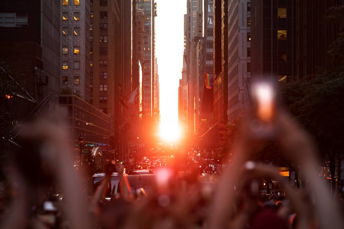 Crowds in the streets trying to photograph the phenomenon known as Manhattanhenge, an NYC bucket list experience