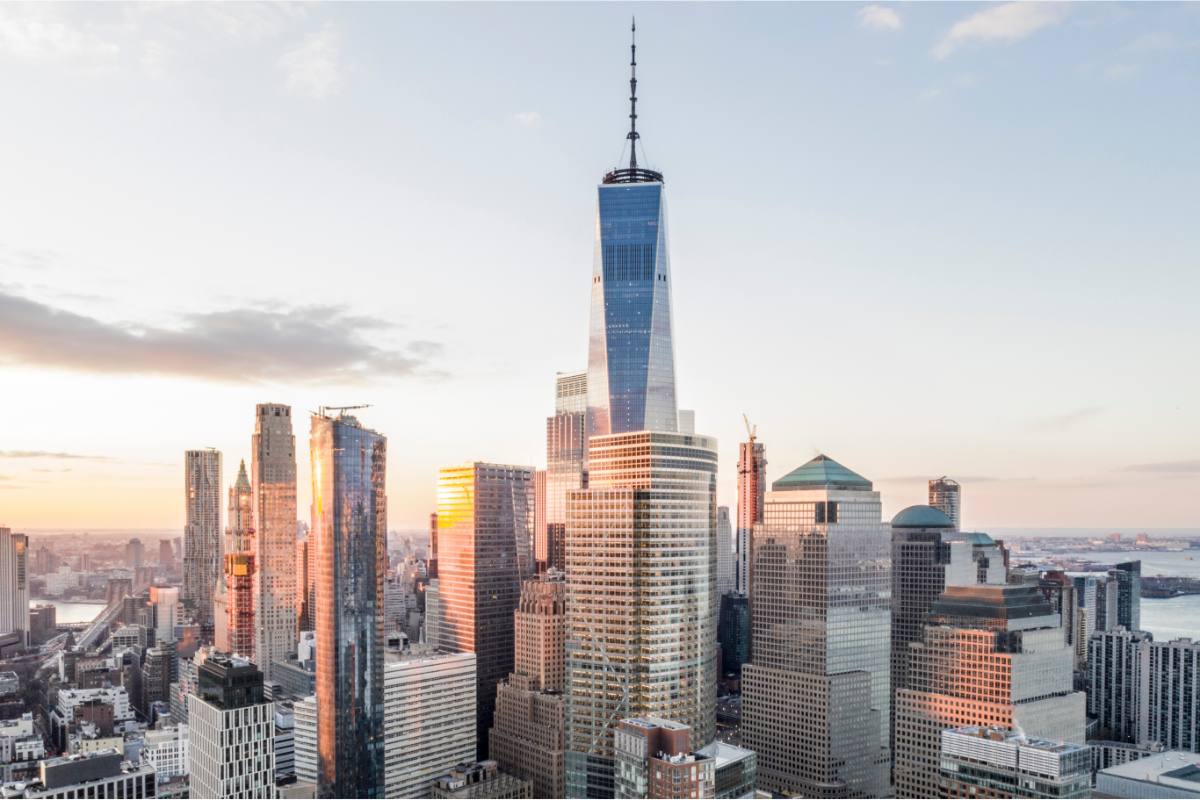 One World Trade Center towering over nearby buildings during sunset